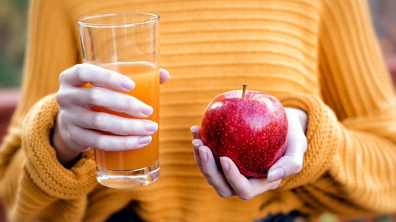 young-woman-holding-glass-of-apple-juice-and-fresh-apple